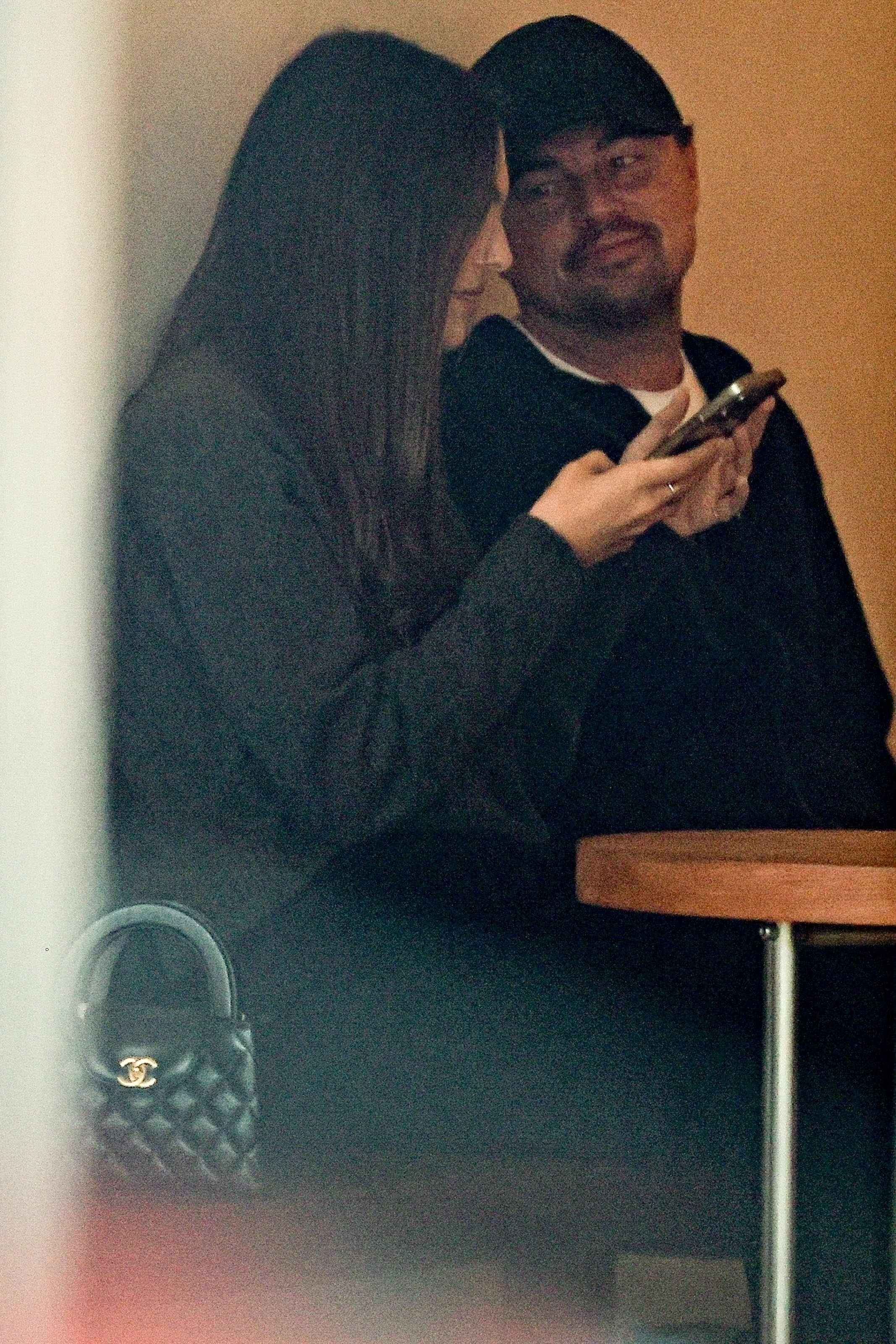 Vittoria Ceretti checking her phone while Leonardo DiCaprio looks on.