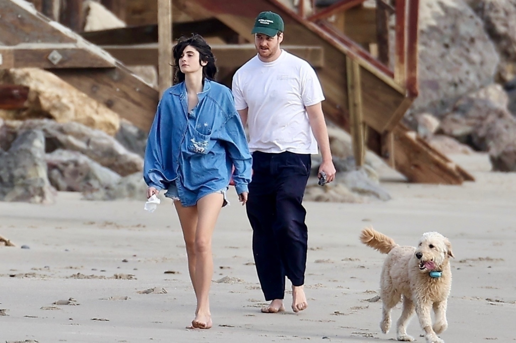 Romy Reiner and Alex Siliberg walking barefoot on Malibu beach with their dog.