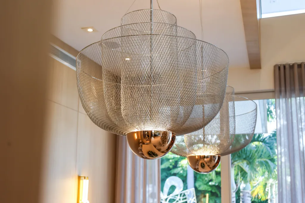 Two modern chandeliers with mesh shades and mirrored copper bulbs.