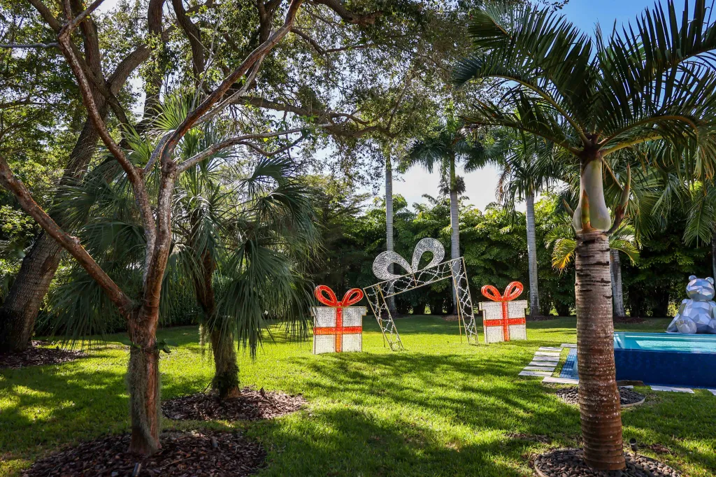Christmas decorations in a tropical backyard with gift box lights and a giant bow arch.