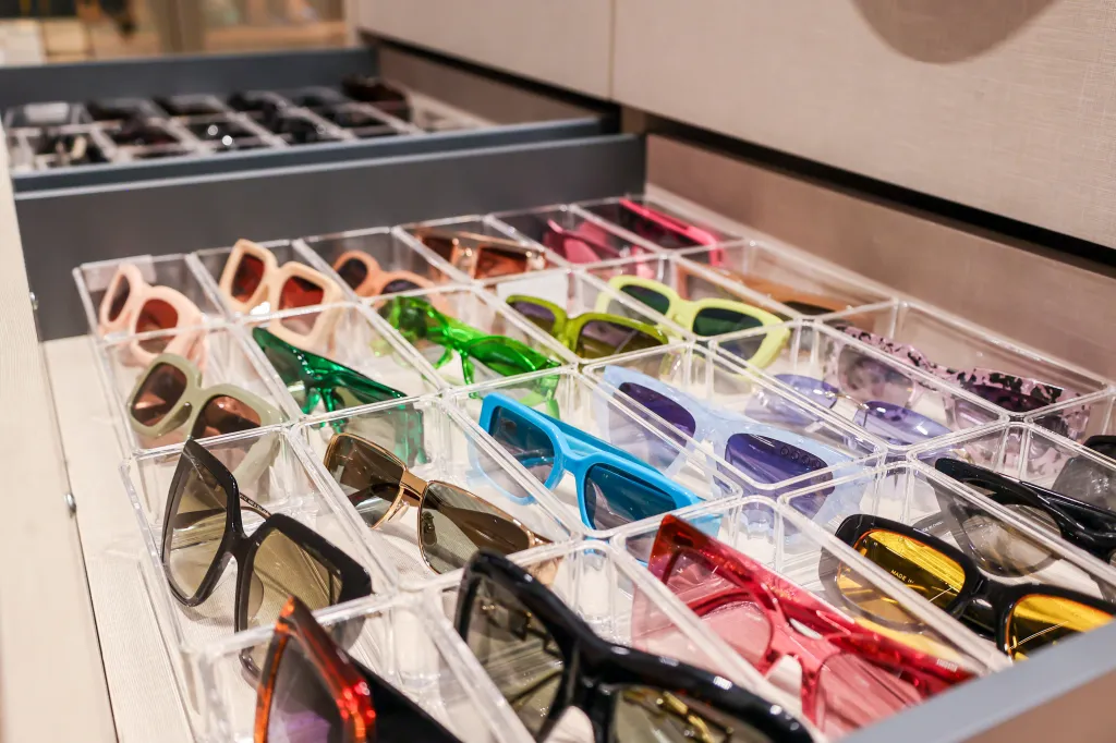Drawers filled with sunglasses in various colors and styles in clear dividers.