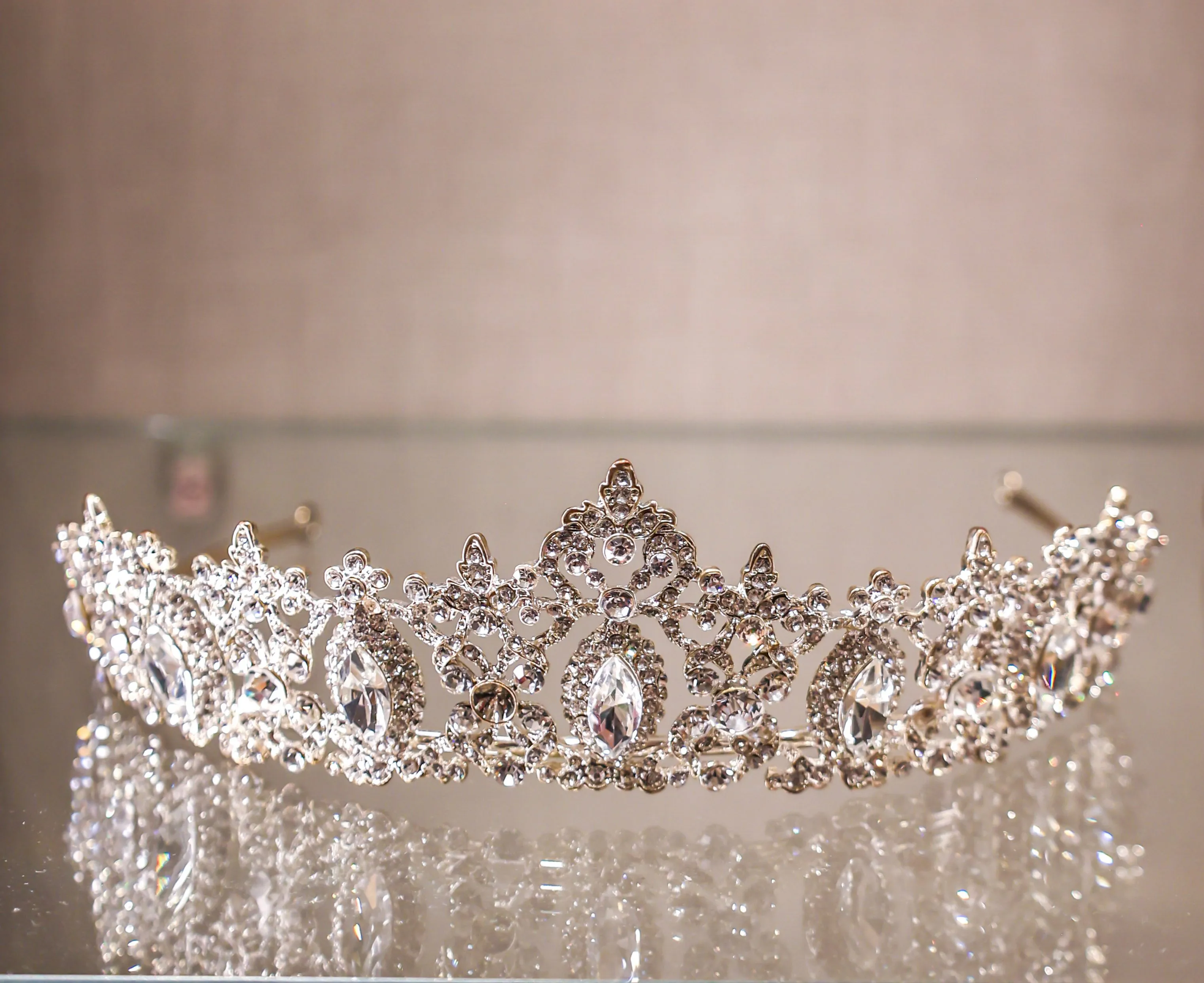 A jeweled tiara on a glass shelf.