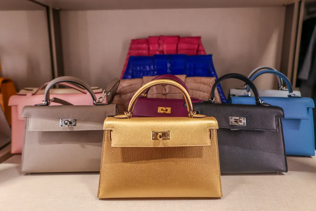 A collection of luxury handbags in various colors arranged on a shelf.