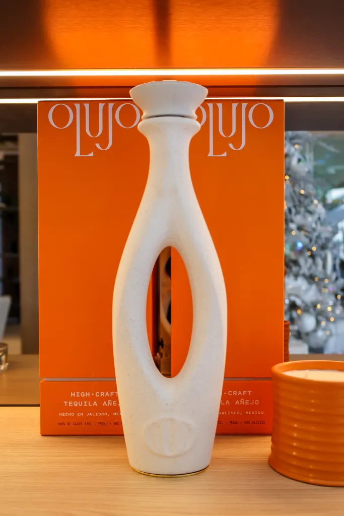 Lujo Tequila bottle and box with a Christmas tree in the background.