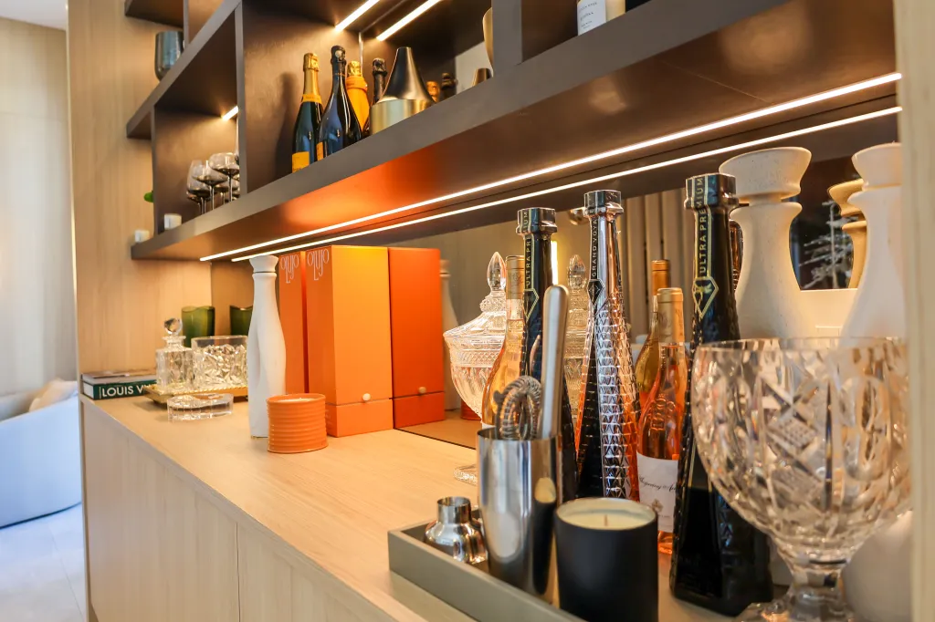 A decorated home bar area with bottles of champagne and wine, glassware, and orange boxes.
