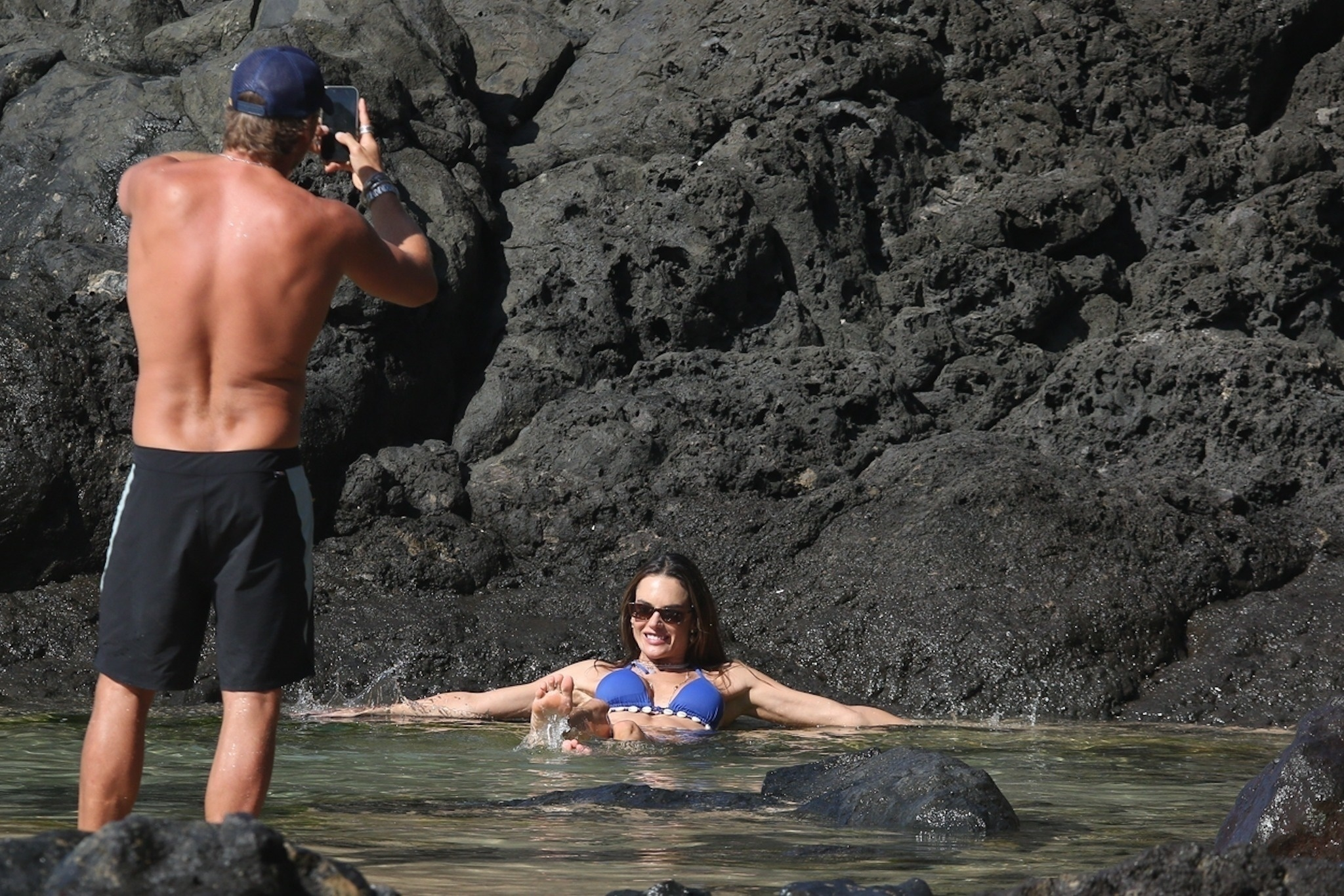 Buck Palmer taking a photo of Alessandra Ambrosio in a shell-studded bikini in the water at Boda Beach.