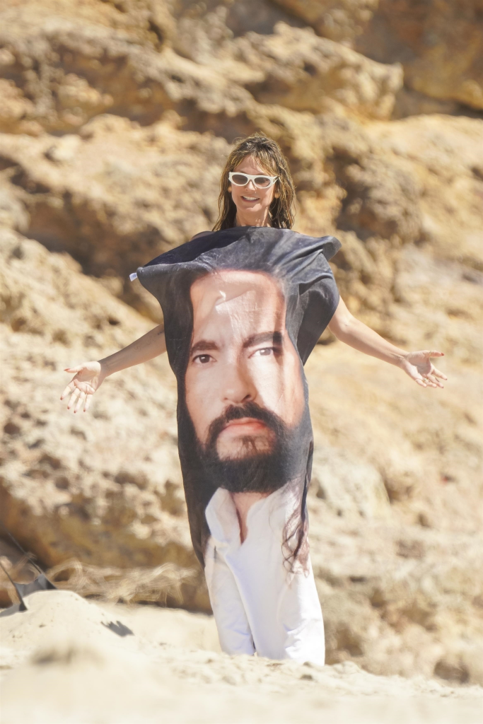 Heidi Klum posing in a Bill Kaulitz t-shirt on a beach.