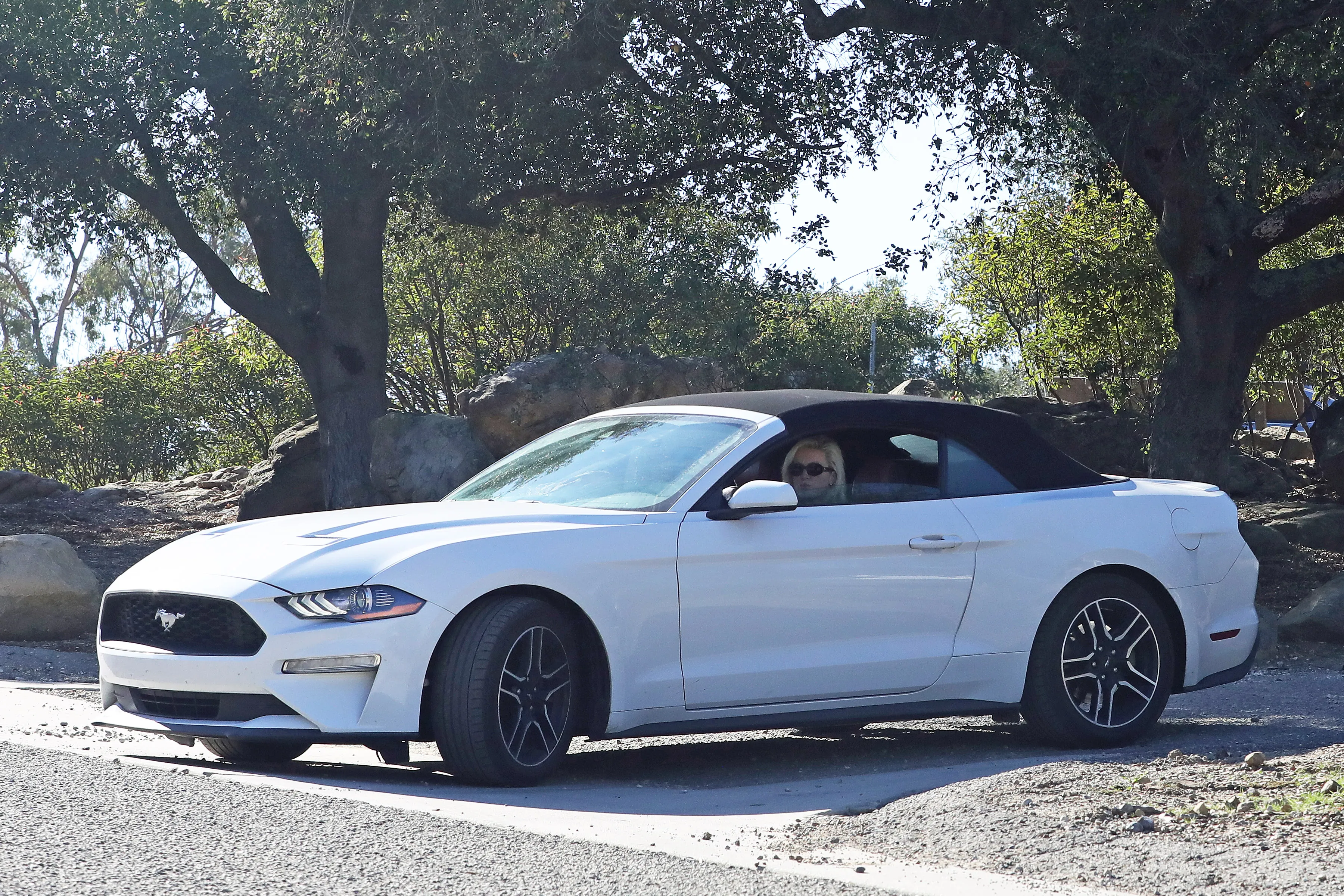 Olivia Nuzzi in a white Ford Mustang convertible.