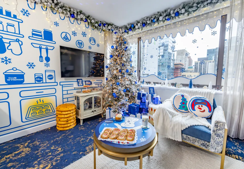 Holiday-themed room with a blue and white decorated Christmas tree, Pillsbury-themed decor, and winter snacks.