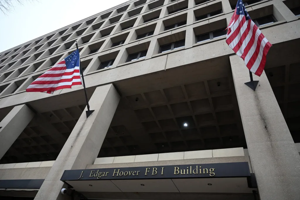 The J. Edgar Hoover FBI Building in Washington, D.C., with two American flags flying on its facade.