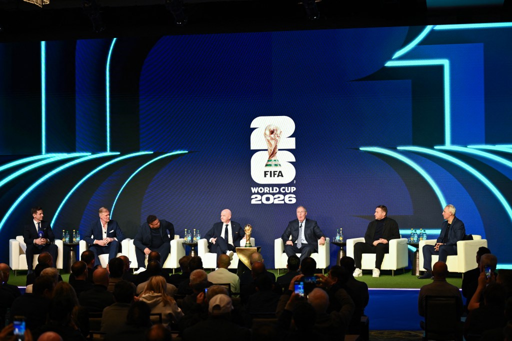 Seven men on stage in white chairs for the FIFA World Cup 2026 schedule announcement.