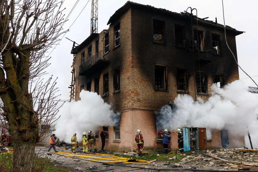 Firefighters extinguish a fire inside a building damaged and left charred by the overnight attack.