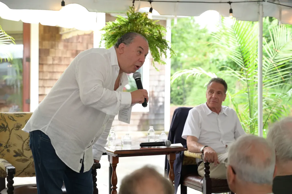 Rabbi Marc Schneier speaking into a microphone while Andrew Cuomo listens.