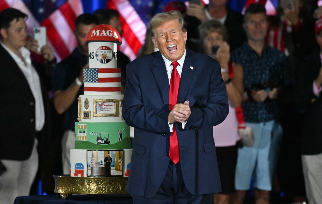 Former US President Donald Trump next to a tiered birthday cake at a campaign rally.