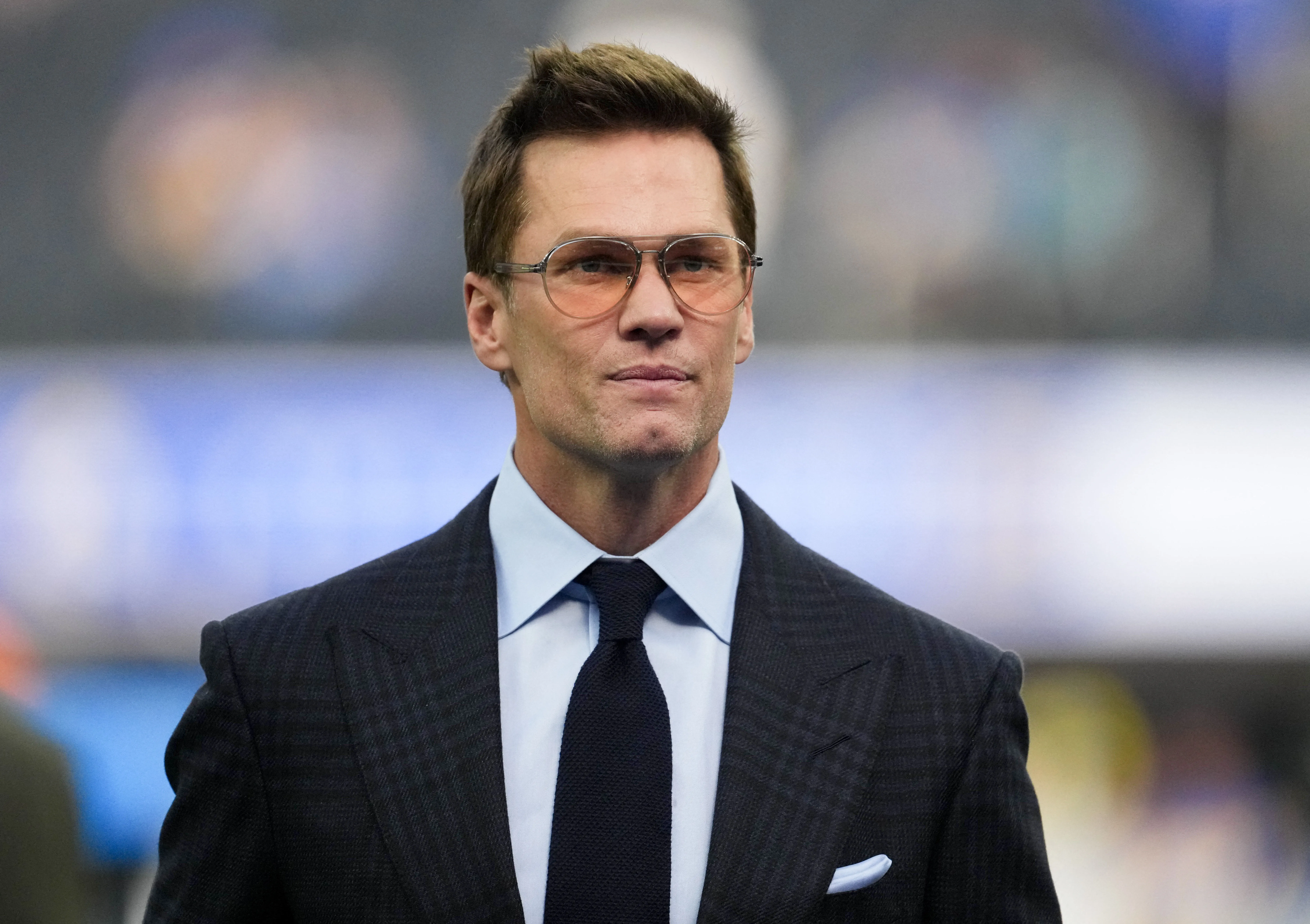 Tom Brady wearing a suit and glasses.