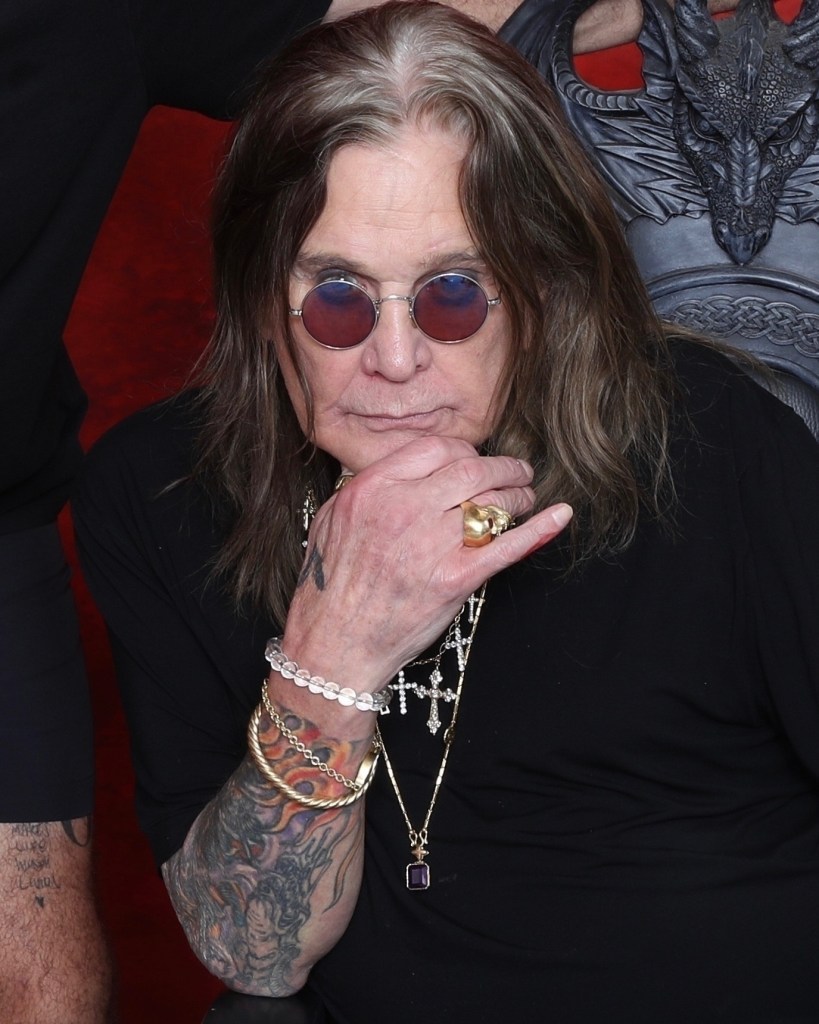Ozzy Osbourne wearing round sunglasses, necklaces, rings, and bracelets.
