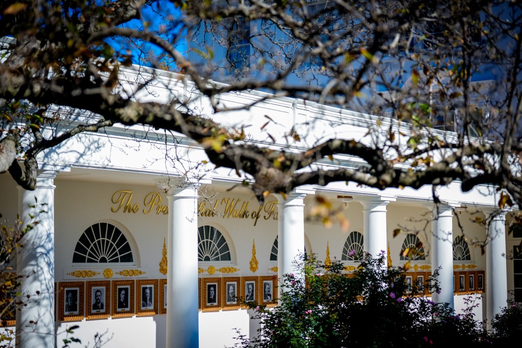 Framed portraits of U.S. presidents hang along the wall of the colonnade with the words