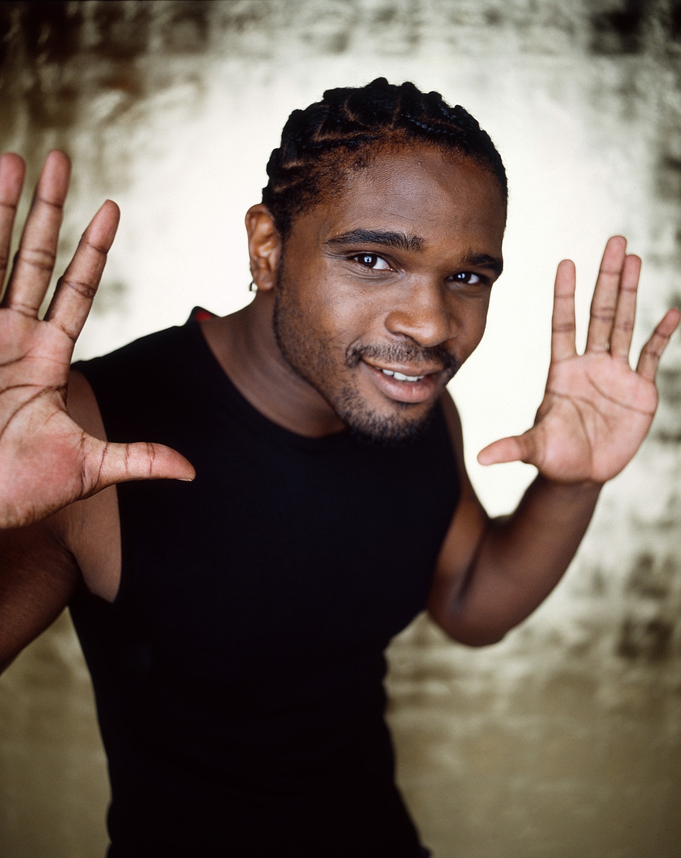 Darius McCrary in a black shirt, palms facing forward.
