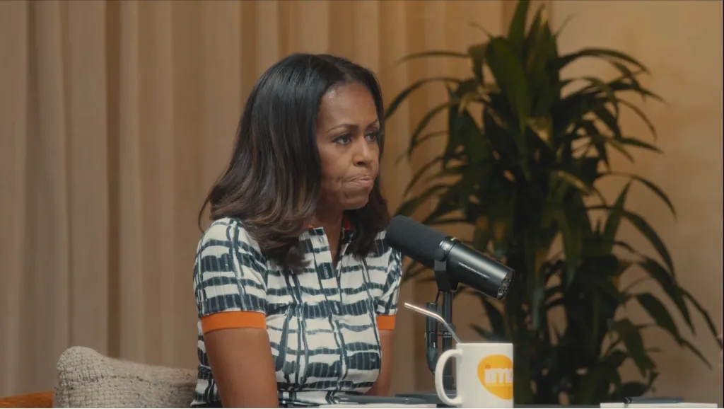 Michelle Obama with a microphone and mug.
