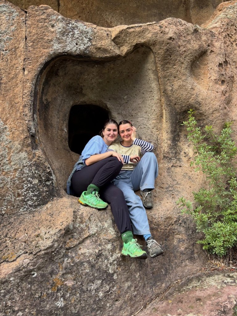Maisie Williams sitting inside a heart-shaped rock formation.