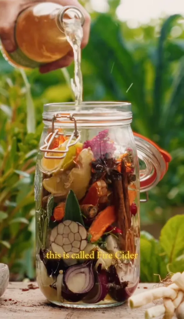 Liquid being poured into a jar filled with ingredients for fire cider.