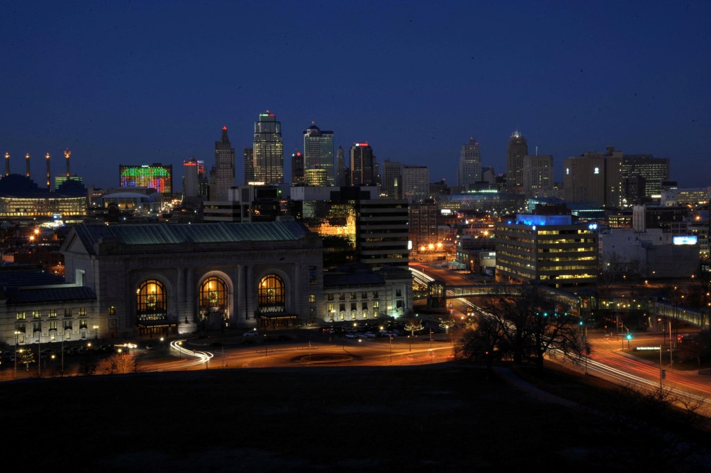 Nighttime view of Kansas City skyline and Union Station with streaking car lights.