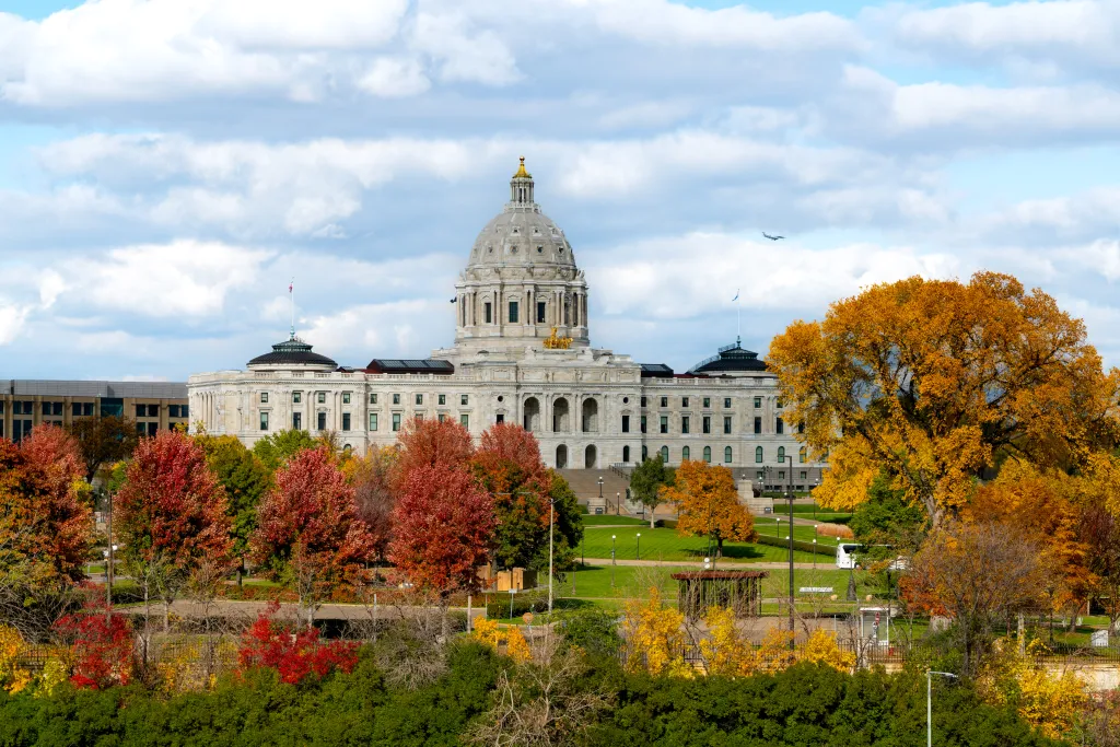The Minnesota State Capitol building in Saint Paul, surrounded by autumn trees with red, orange, and yellow foliage.