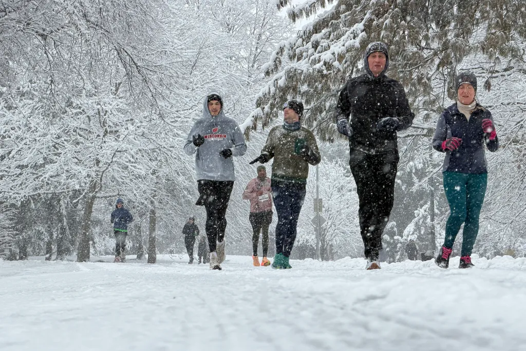 People running in Prospect Park during a snowstorm.