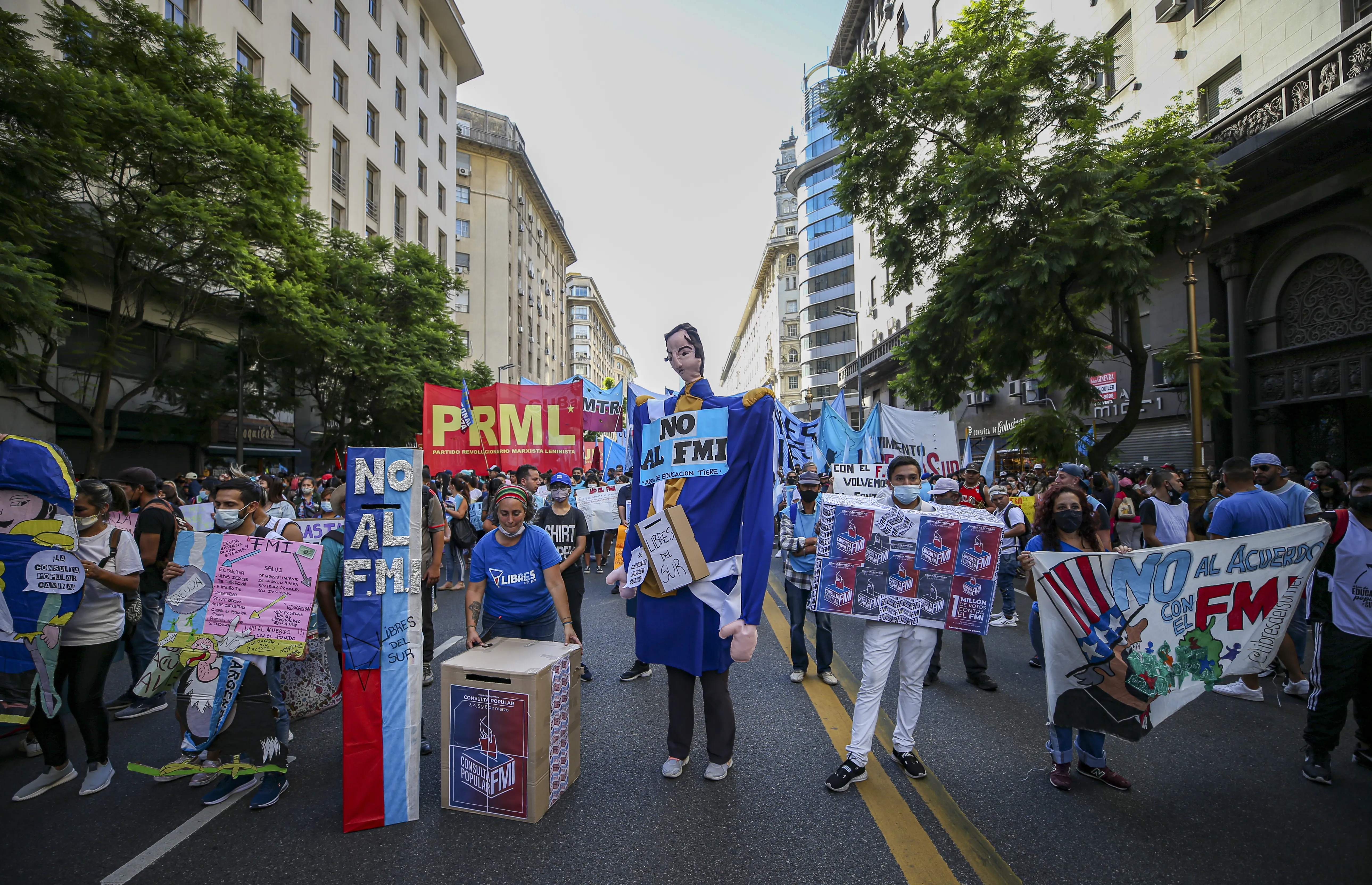 A group of protesters in Argentina hold colorful signs denouncing the IMF and austerity.