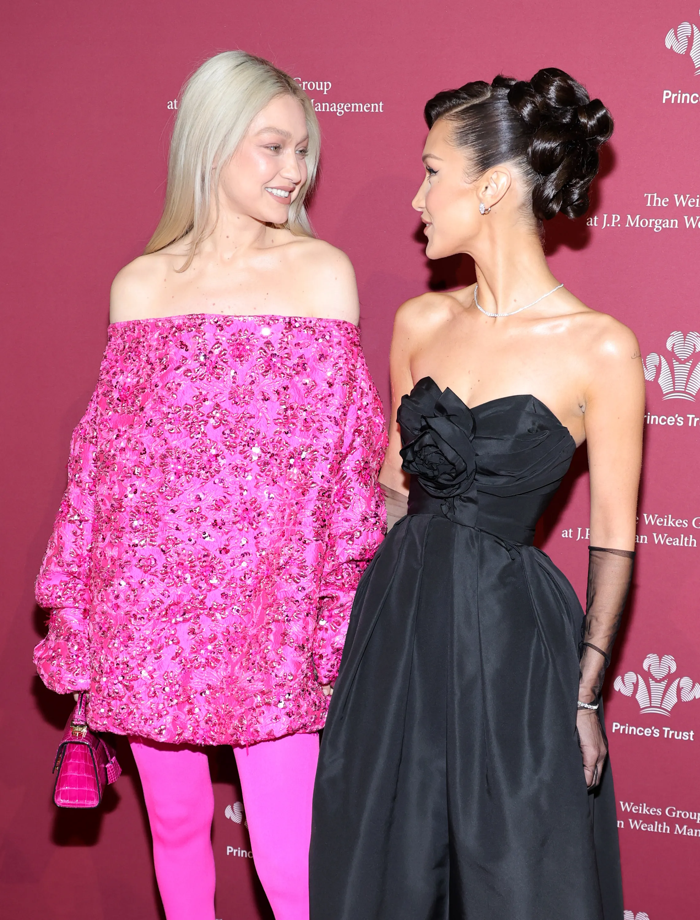 Gigi Hadid in a bright pink off-the-shoulder top and Bella Hadid in a black strapless gown attend the 2022 Prince's Trust Gala.