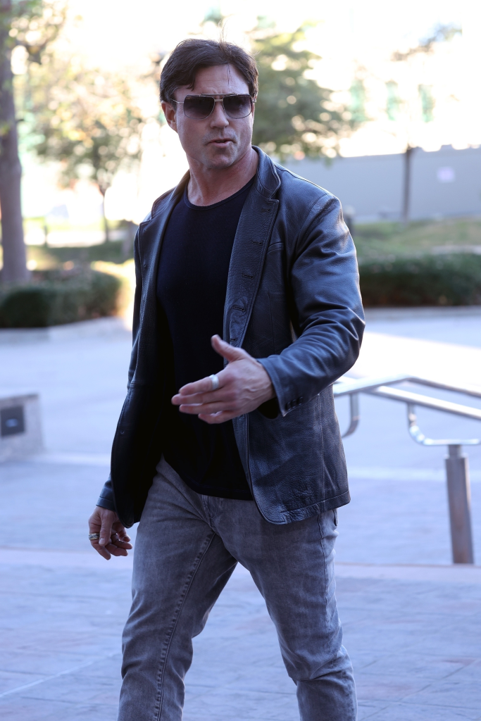 Aaron Phypers in sunglasses and a dark leather jacket outside a courthouse.