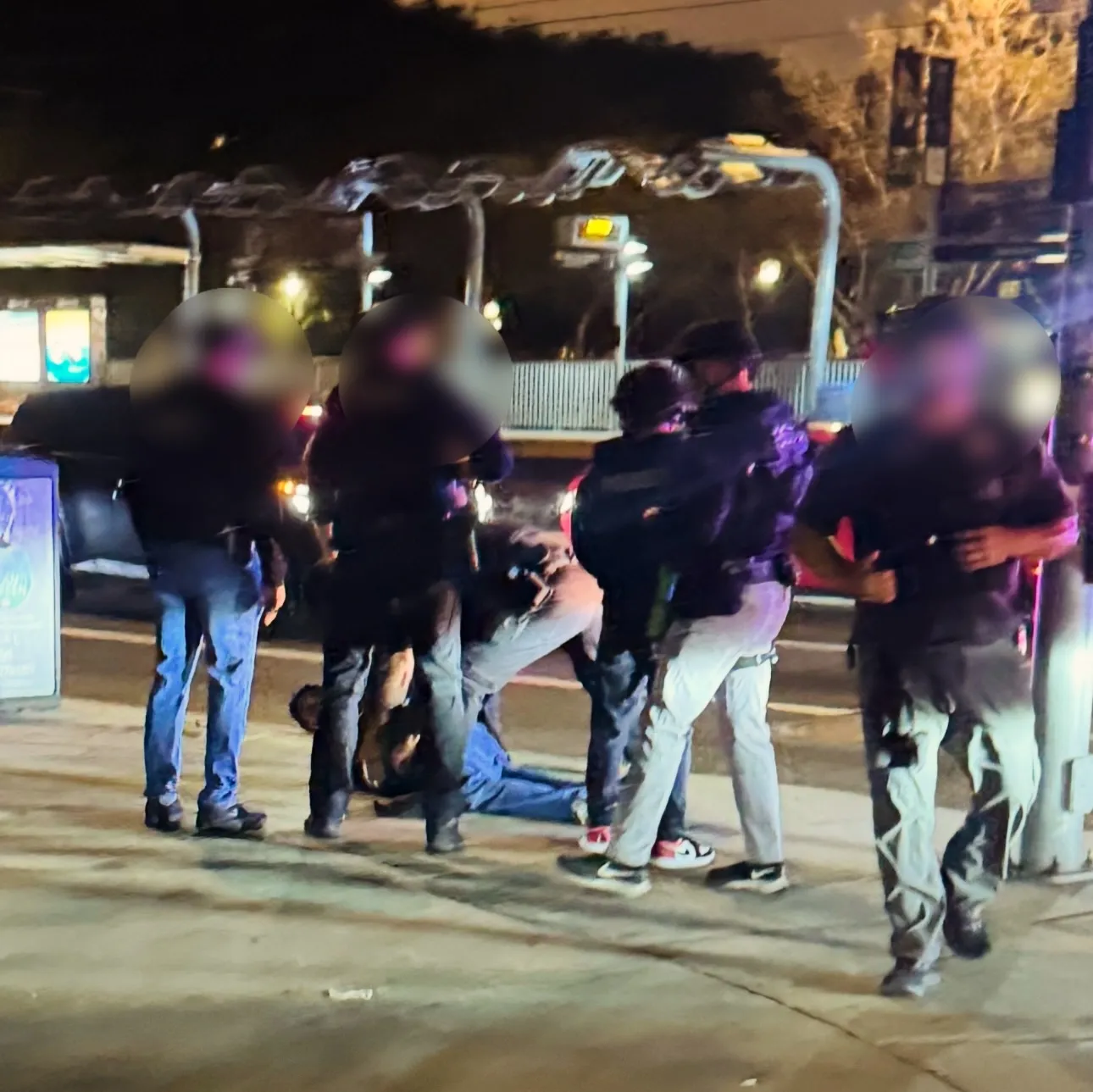 Law enforcement officers arresting a person on the ground at night.