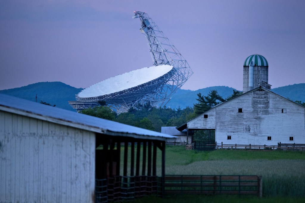 Green Bank Telescope behind a farm at dusk.