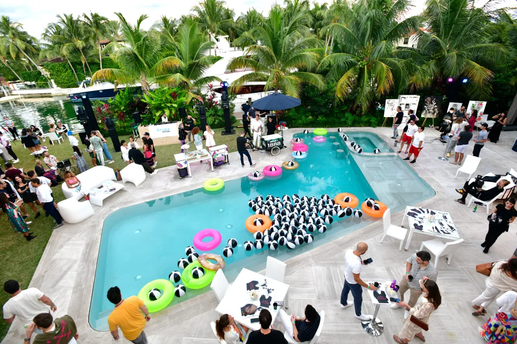 Guests attending the NYLON House pool take-over at Art Basel Miami, with pool toys and art displays.