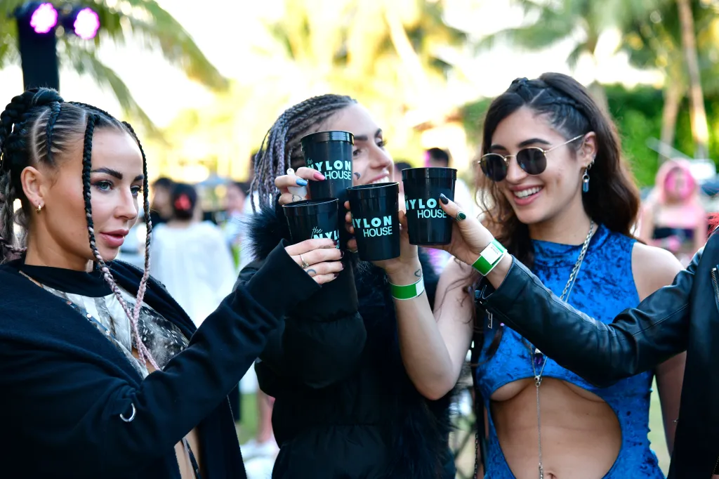 Three women wearing green wristbands toast with black 