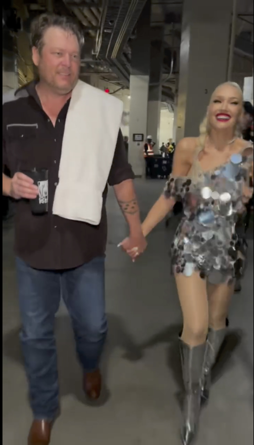 Blake Shelton and Gwen Stefani hold hands while walking together backstage.