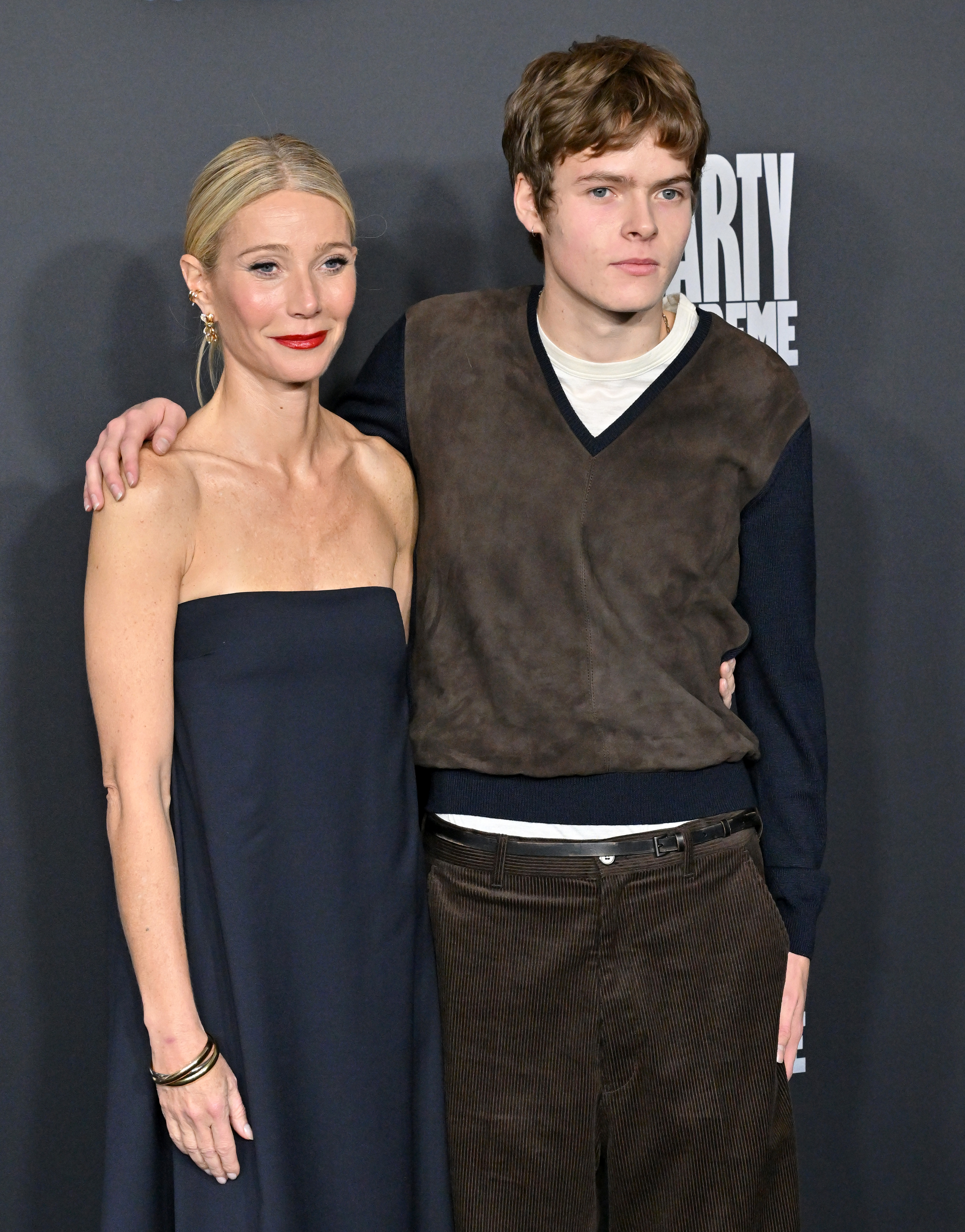 Gwyneth Paltrow in a black strapless dress and Moses Martin in a brown suede and black sweater with brown corduroy pants.