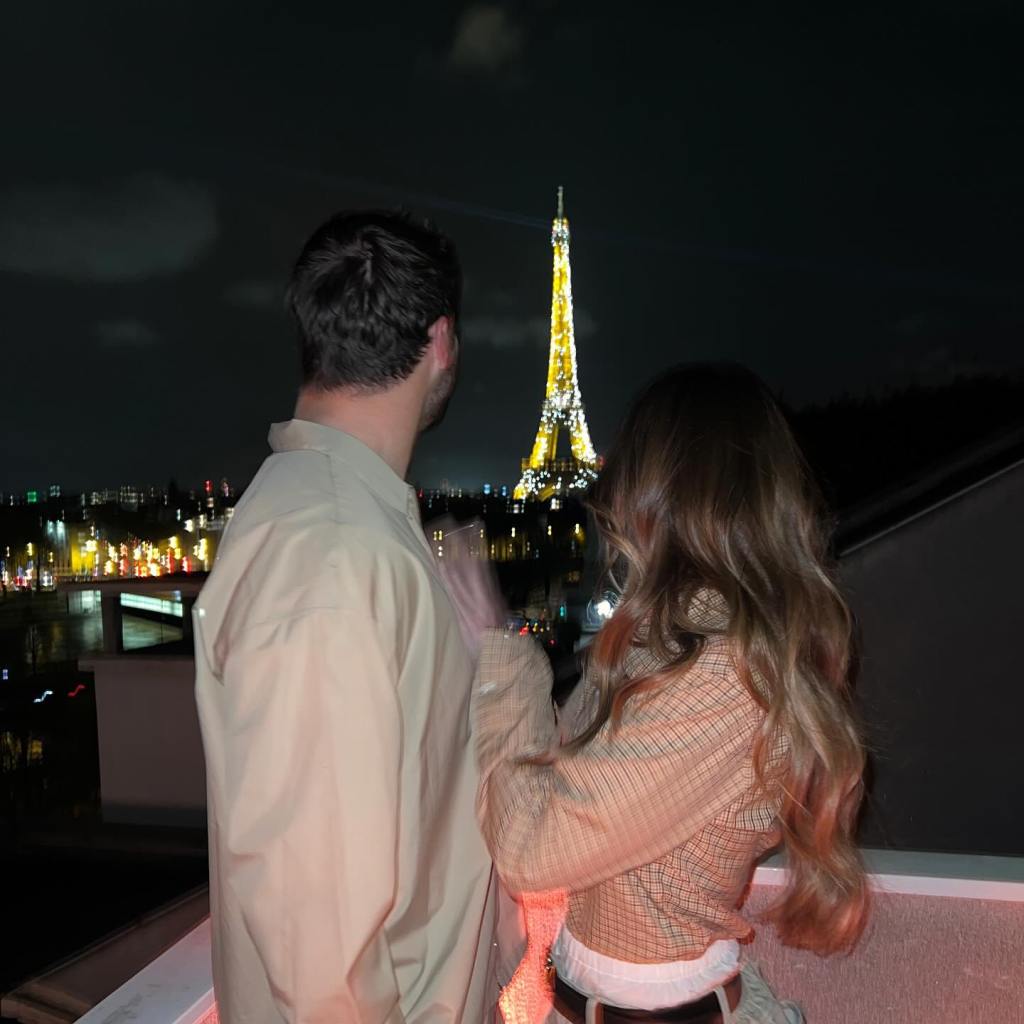 Hailee Steinfeld and Josh Allen admiring the Eiffel Tower at night.