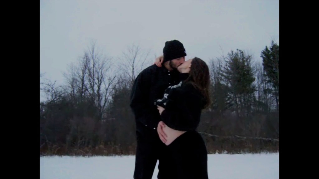 Hailee Steinfeld and Josh Allen kissing in a snowy landscape, with Steinfeld revealing her baby bump.