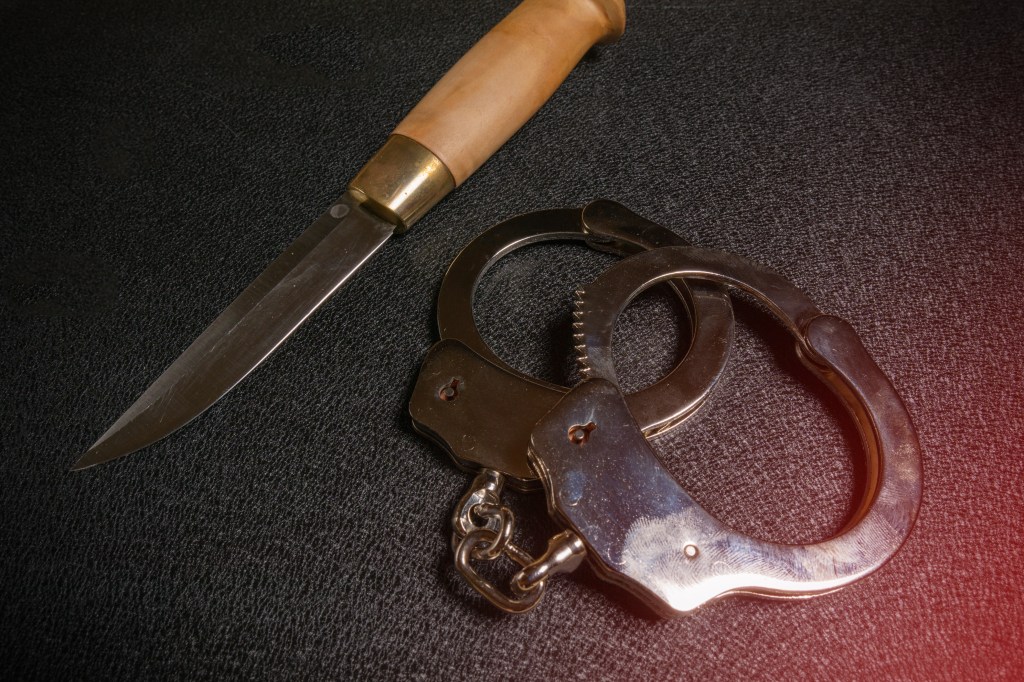 Handcuffs and a knife on a black table.