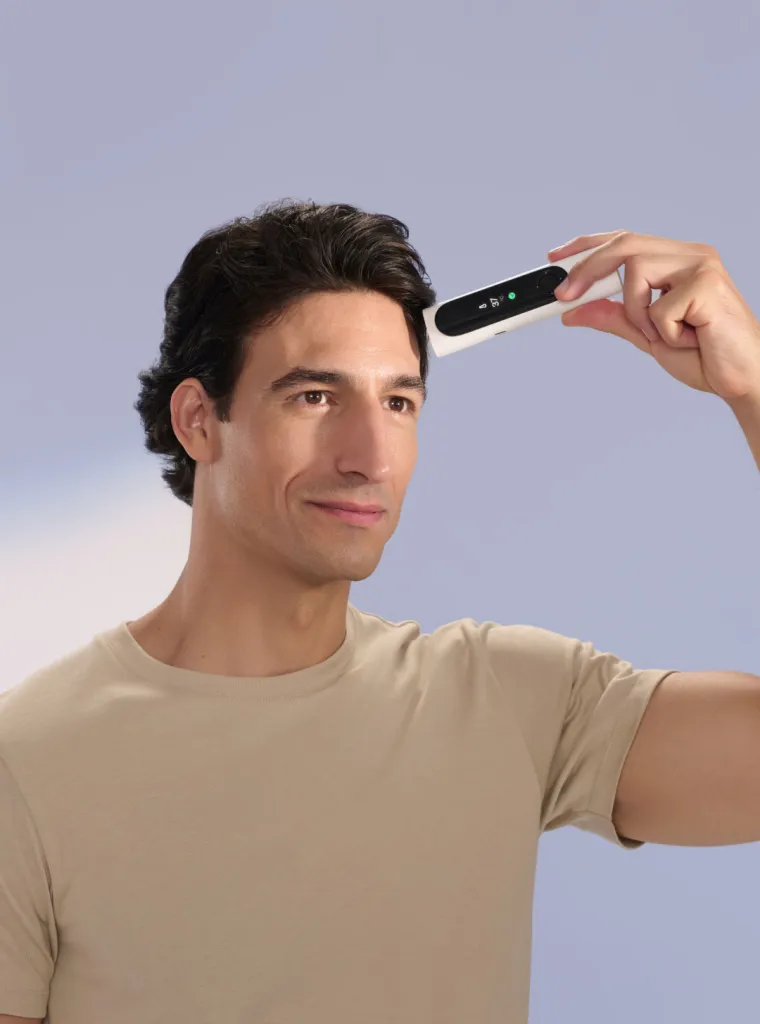 Man measuring his temperature with a BeamO thermometer on his forehead.