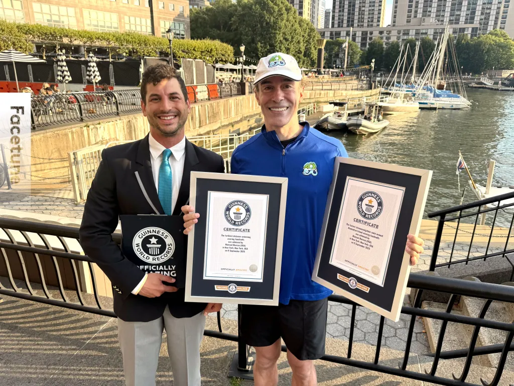 Michael Moreau (right) holding Guinness World Records certificates for swimming in handcuffs.