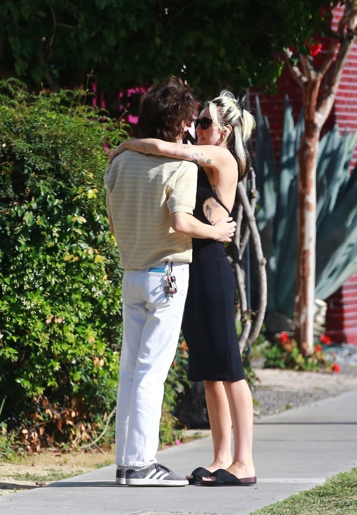 Miley Cyrus and Maxx Morando embracing while standing outside.