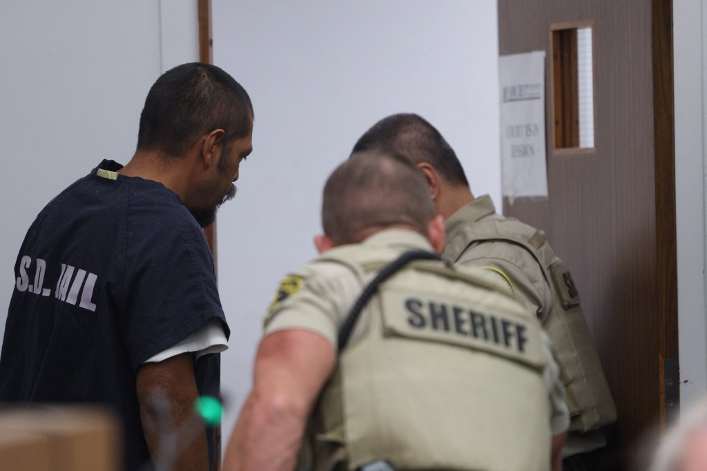 Hector Balderas-Aheelor (aka Hector Amador Balderas) being escorted out of court by two sheriff's deputies.