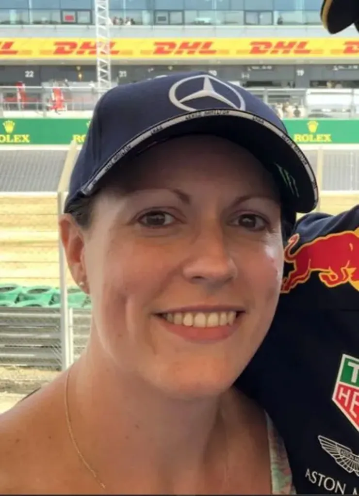 Helen Eisenhauer, a woman in a Mercedes-Benz hat, smiling at a racetrack.