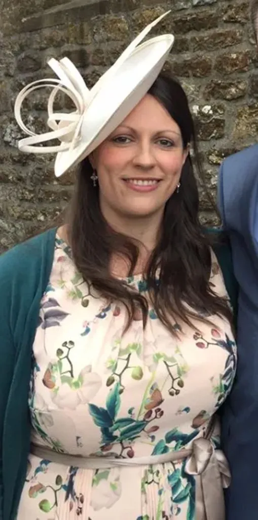 Helen Eisenhauer smiling, wearing a white fascinator, patterned dress, and dark green cardigan.