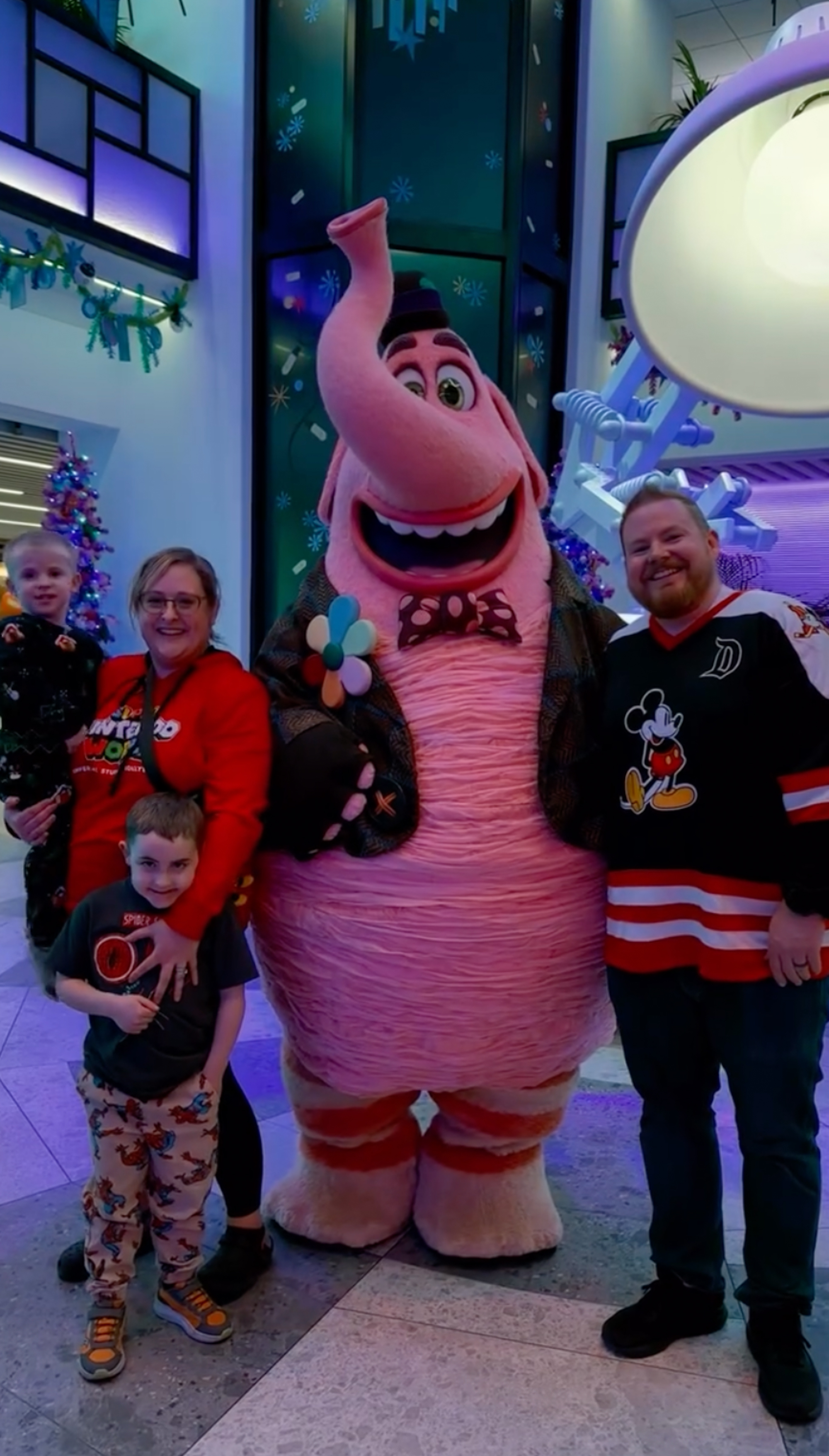 A family of four, including two young boys, posing with the Bing Bong character from Inside Out.