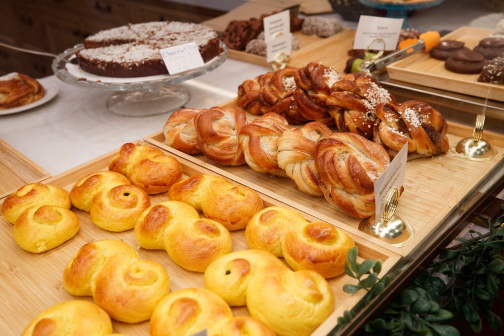 Baked goods on display, including saffron buns, cardamom buns, and chocolate cake.