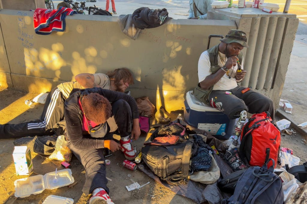 Three homeless people rest at MacArthur Park.