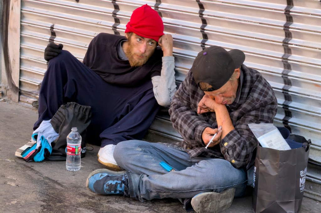 Homeless people rest at MacArthur Park Wednesday Dec. 10, 2025, in Los Angeles. 